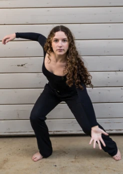 Serendipity dancer reaching through a low dance pose